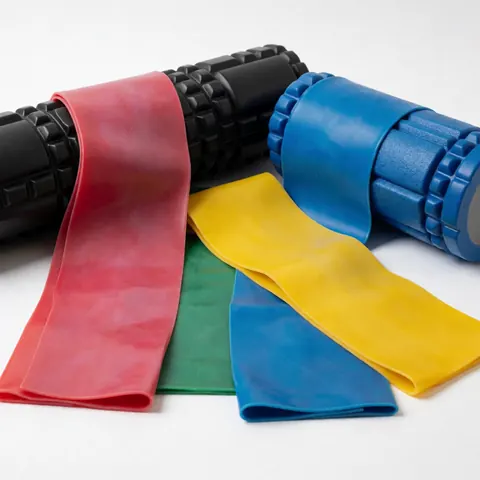 Bandes élastiques et rouleaux de massage en couleurs sur fond blanc pour la rééducation et le fitness.