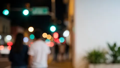 Arrière-plan abstrait de ville la nuit avec des feux de circulation et des lampadaires flous, laissant un espace vide à droite pour ajouter du texte, idéal pour les projets commerciaux en milieu urbain.