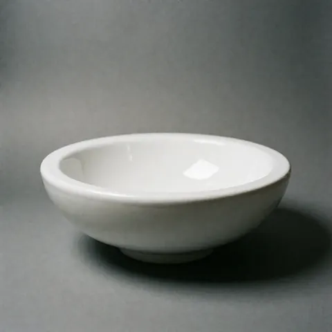 Un évier en céramique blanche posé sur un fond gris avec une illumination douce et minimaliste, idéal pour la décoration de salle de bain ou cuisine.