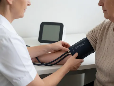 Une infirmière utilise un moniteur numérique pour vérifier la tension d'un patient dans un cabinet médical lumineux et propre.
