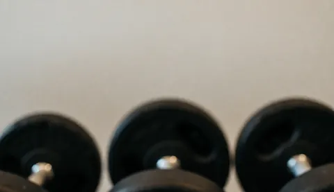 Arrière-plan sombre et abstrait mettant en valeur des haltères hors focus pour un texte ou une publicité fitness.