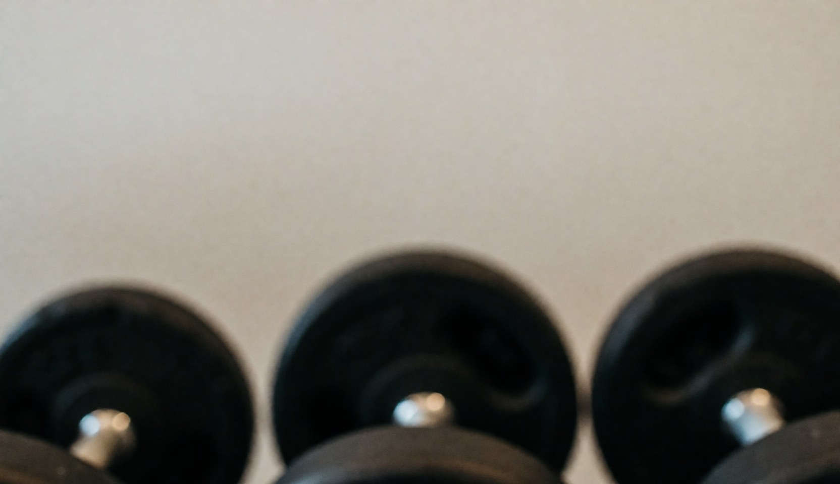 Arrière-plan sombre et abstrait mettant en valeur des haltères hors focus pour un texte ou une publicité fitness.