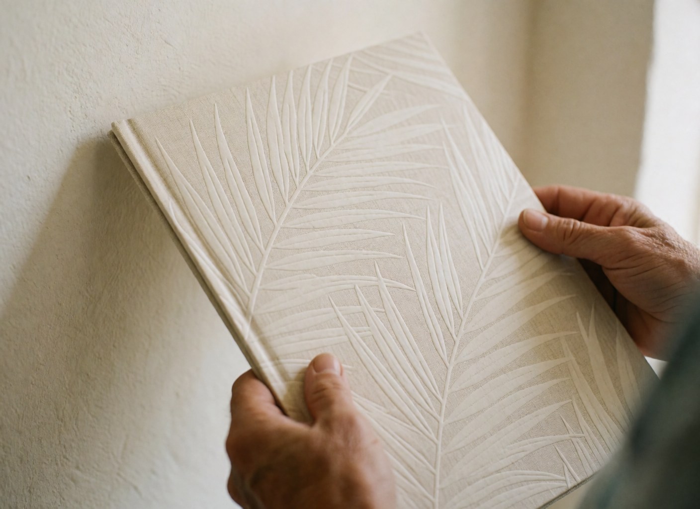 Mains tenant une brochure de voyage ornée de feuilles de palmier sur un fond blanc évoquant le luxe et les détails.