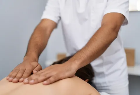 Un thérapeute réalise un massage facial professionnel sur une cliente dans un cadre de bien-être.