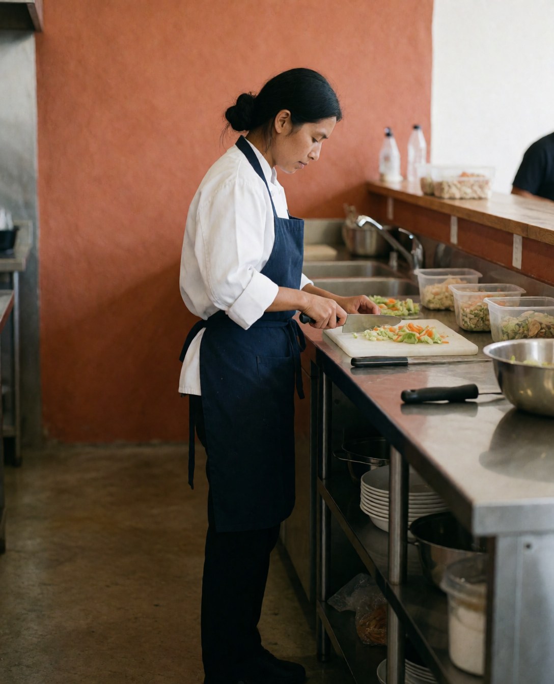 Vue rapprochée de la préparation soignée des ingrédients frais sur une planche à découper dans un environnement de cuisine professionnelle.