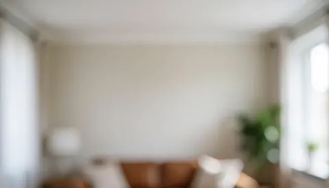 Intérieur minimaliste avec un canapé marron, une fenêtre laissant entrer la lumière naturelle et une plante verte sur fond blanc, idéal pour des présentations professionnelles.