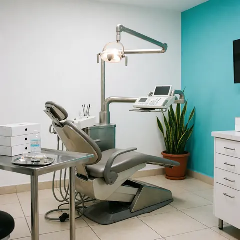 Caméra dentaire sur chaise avec mur turquoise et plante dans un environnement professionnel et hygiénique de cabinet dentaire.