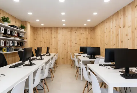 Vue intérieure d'un espace de travail moderne et ordonné avec bureau en bois, chaise, écran d'ordinateur, clavier et câbles organisés.