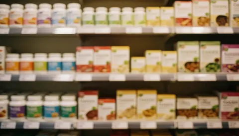 Arrière-plan flou d'étagères contenant des compléments alimentaires et des boîtes de produits sains dans un magasin, aux tons chauds et apaisants.