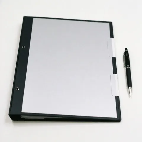 Dossier professionnel avec un stylo noir posé dessus, sur un fond blanc uni, évoquant les affaires et la négociation.