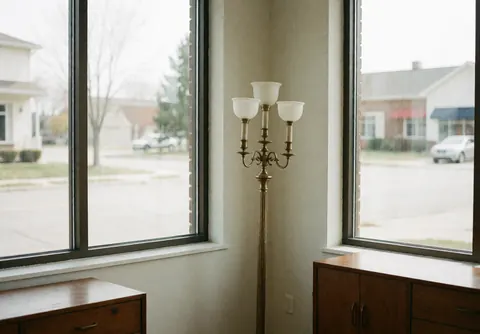Vue intérieure d'une boutique de mobilier moderne avec lampadaire, grandes fenêtres laissant entrer la lumière naturelle et sols clairs.