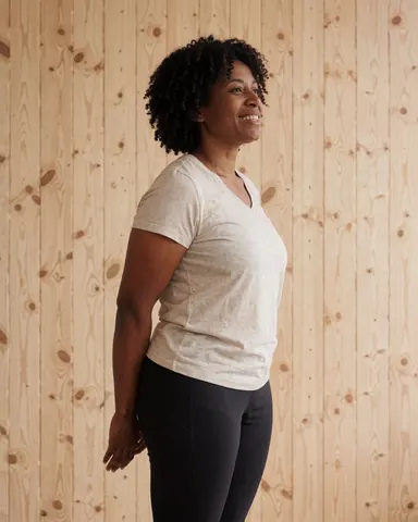 Une femme souriante effectue des étirements après une séance de yoga ou pilates dans un intérieur lumineux.