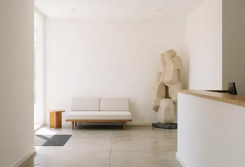Réception d'architecture moderne avec canapé, sculpture abstraite et lumière naturelle créant un environnement propre et lumineux.
