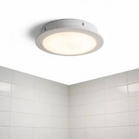 Luminaire LED circulaire installé au plafond dans une salle de bain moderne avec carrelage blanc, offrant un éclairage intérieur clair et design.