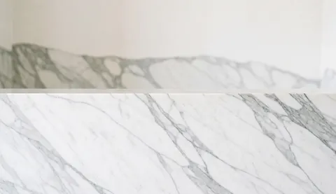 Surface en marbre blanc veiné de gris servant de fond élégant et minimaliste pour l'ajout de texte dans un contexte immobilier ou design d'intérieur.