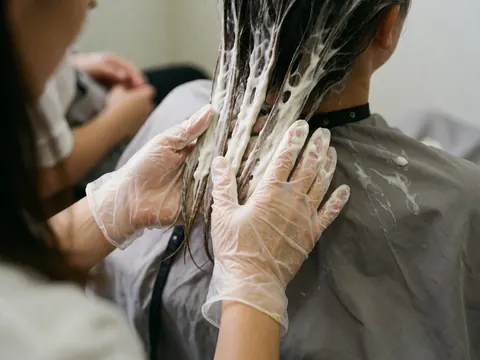 Application minutieuse d'un soin capillaire à base de quinoa sur les cheveux, mettant en valeur un traitement naturel pour le cuir chevelu.