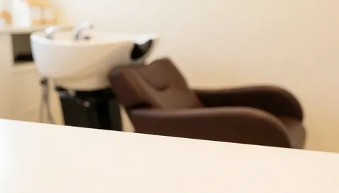Arrière-plan d'un salon de coiffure montrant un fauteuil de lavage et un lavabo, idéal pour des textes sur les services de beauté et les soins capillaires.