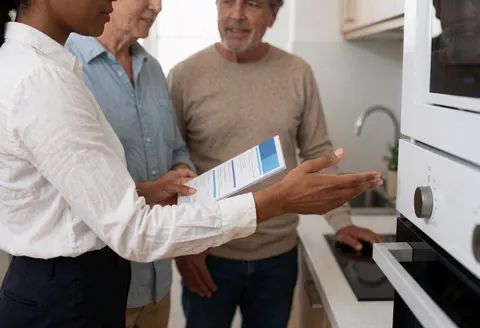 Un agent immobilier explique les caractéristiques de la cuisine à des clients intéressés lors d'une visite de propriété.