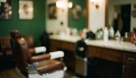 Arrière-plan flou d'un intérieur de barbier avec un mur vert foncé, un comptoir en marbre et une chaise en cuir pour texte.