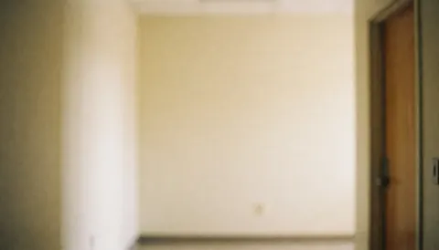 Intérieur d'un couloir de centre communautaire aux murs beige, encadrement en bois et lumière chaude, fond flou adapté au texte ou aux présentations.