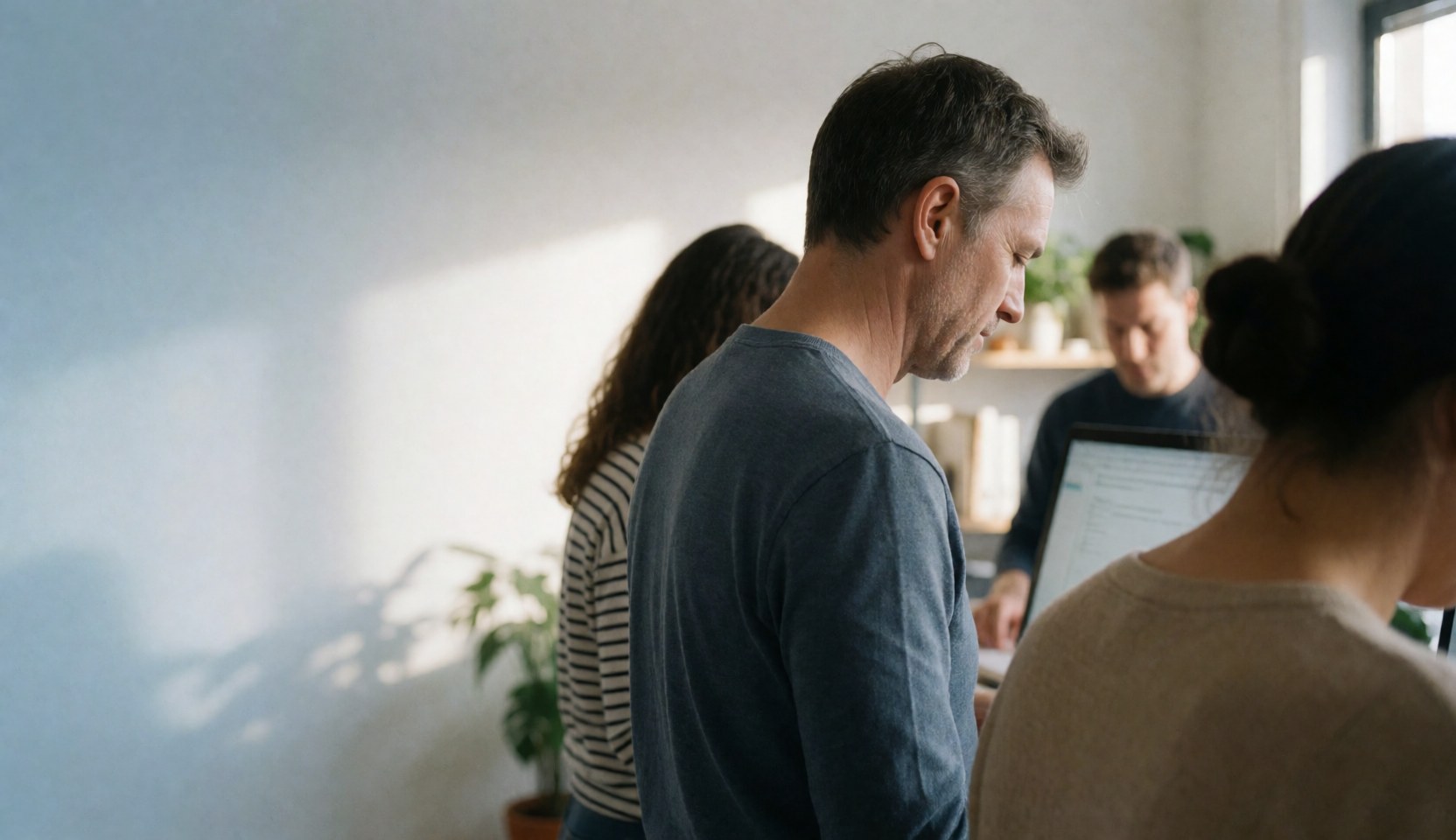 Une équipe professionnelle d'agents immobiliers collaborant autour d'un bureau avec des ordinateurs portables dans un espace de travail lumineux et contemporain.