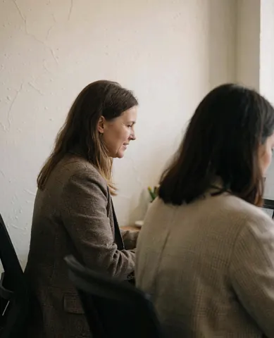 Une femme professionnelle participe à une visioconférence depuis son bureau.