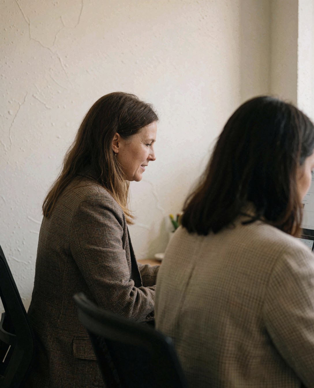 Une femme professionnelle participe à une visioconférence depuis son bureau.