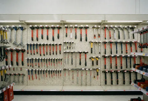 Vue d'un rayon bien rangé d'une quincaillerie présentant divers outils manuels et électriques disposés sur des étagères.