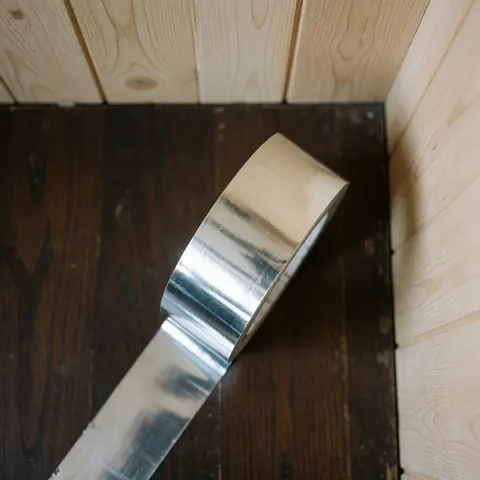 Un rouleau de ruban adhésif posé sur une surface en bois, utilisé pour l'installation et le raccordement dans les systèmes de climatisation.