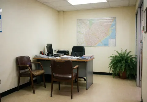 Vue d'un bureau d'auto-école équipé d'un bureau, d'une chaise, d'un ordinateur et d'une grande carte murale.
