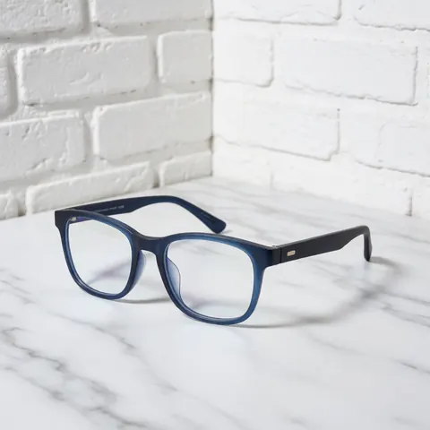 Des lunettes de protection contre la lumière bleue posées sur une surface en marbre blanc avec un mur de briques en arrière-plan.