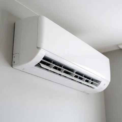 Vue d'une unité intérieure de climatiseur mural blanc au design minimaliste, installée sur un mur clair dans un intérieur lumineux et épuré.