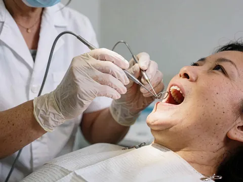 Un dentiste effectue un examen dentaire de routine sur un patient allongé dans le fauteuil, utilisant des outils professionnels.