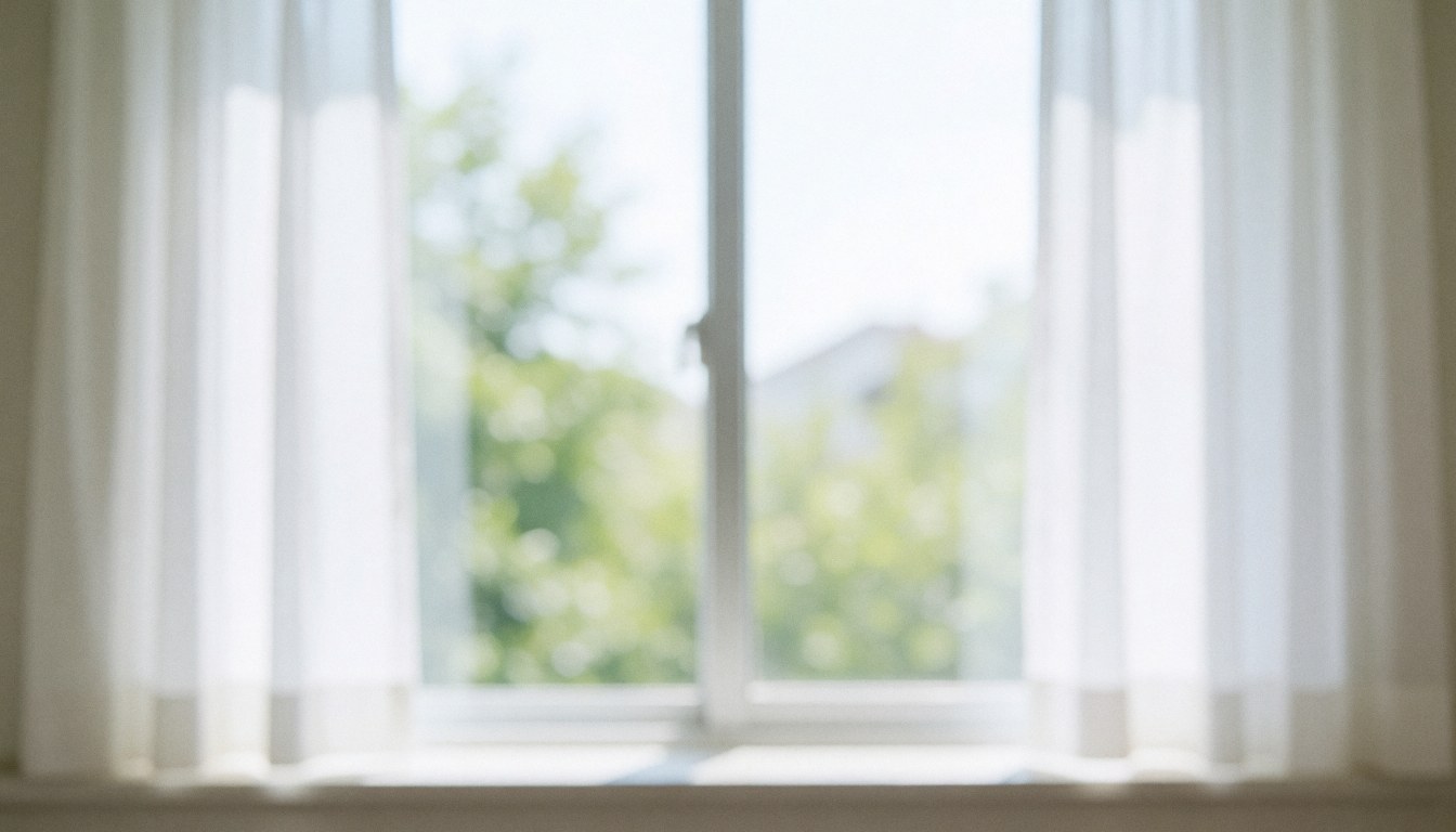 Vue d'une fenêtre laissant entrer la lumière naturelle dans un intérieur de clinique dentaire avec des rideaux blancs, évoquant calme et professionnalisme.