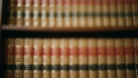 Arrière-plan composé de livres de droit sur une étagère aux tons chauds, idéal pour les avocats et cabinets juridiques. Espace pour texte superposé en haut.