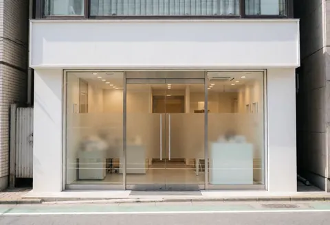 Façade d'une clinique dentaire contemporaine avec portes vitrées, éclairage chaleureux et intérieur visible, idéal pour l'identité de marque.