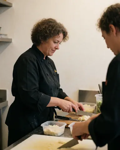 Chef professionnel regardant l'objectif dans une cuisine moderne et bien éclairée, tenant des ustensiles de cuisine.