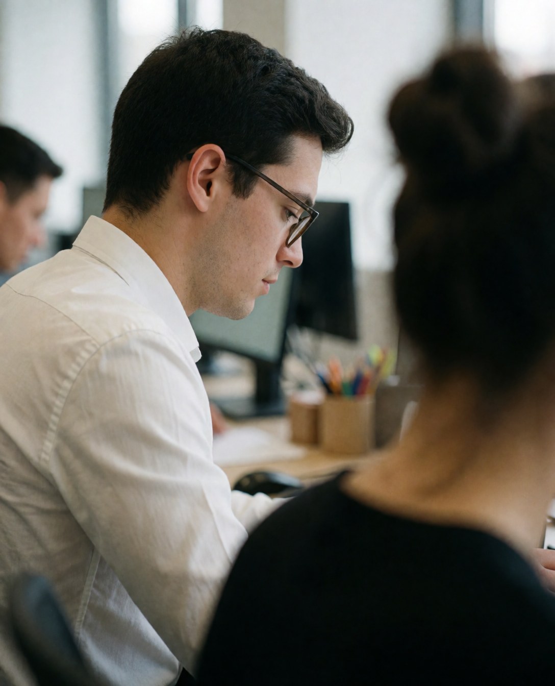 Portrait d'un jeune homme concentré travaillant sur un ordinateur dans un bureau moderne avec une lumière naturelle.
