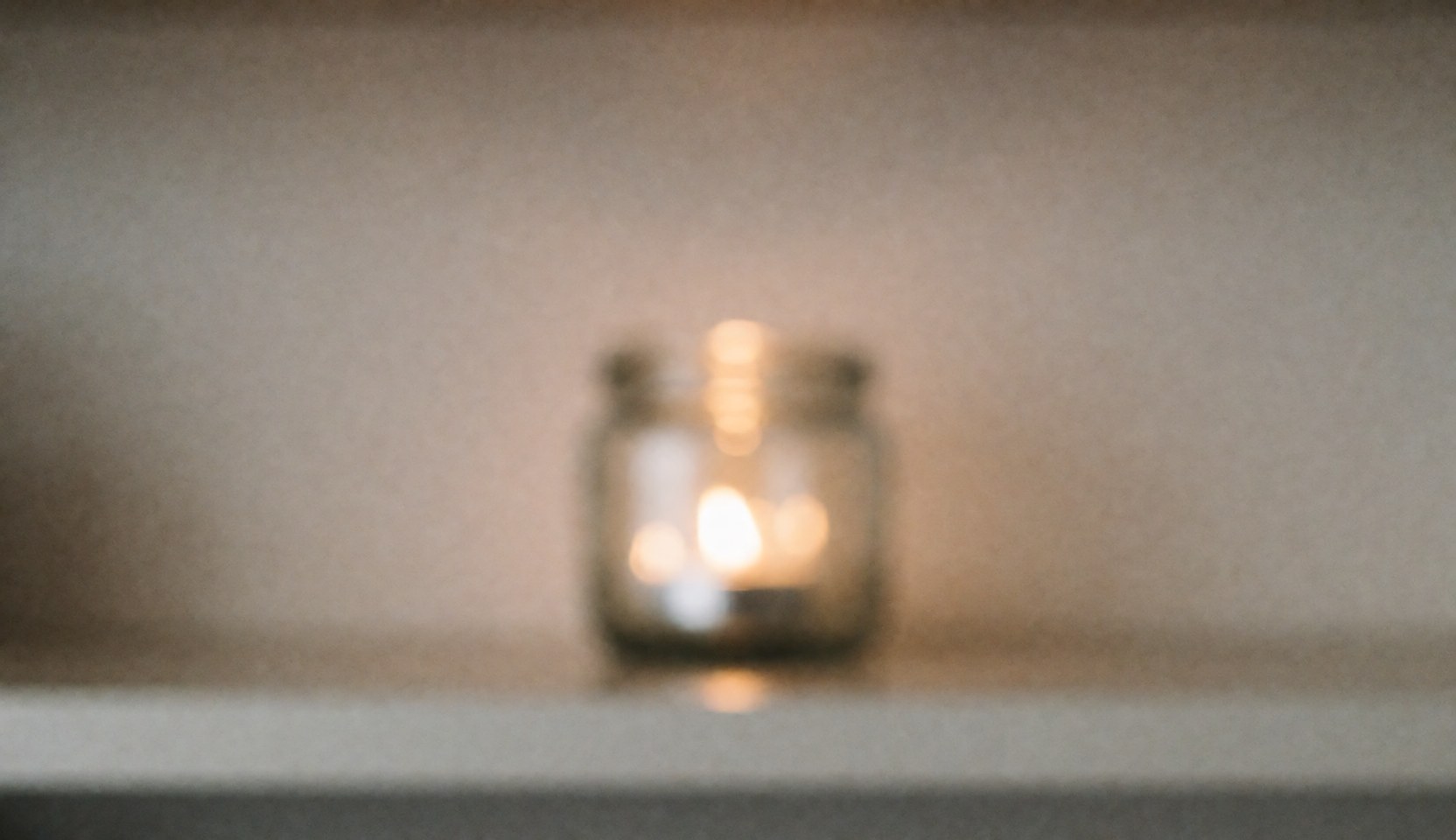 Fond de spa avec une bougie allumée dans un bocal en verre, lumières chaudes et ambiance relaxante, idéal pour les textes sur le bien-être et les massages.