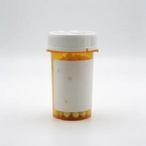 Un flacon de médicaments posé sur un fond blanc uni, représentant un produit pharmaceutique.