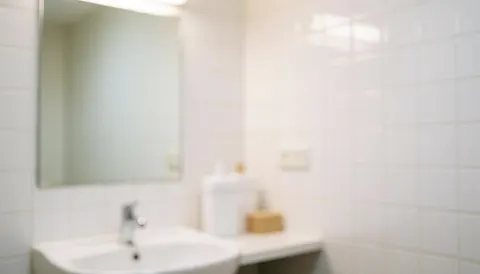 Vue d'un miroir posé sur une vasque dans une salle de bain aux carreaux blancs, offrant un fond lumineux et épuré idéal pour des textes ou présentations professionnelles.