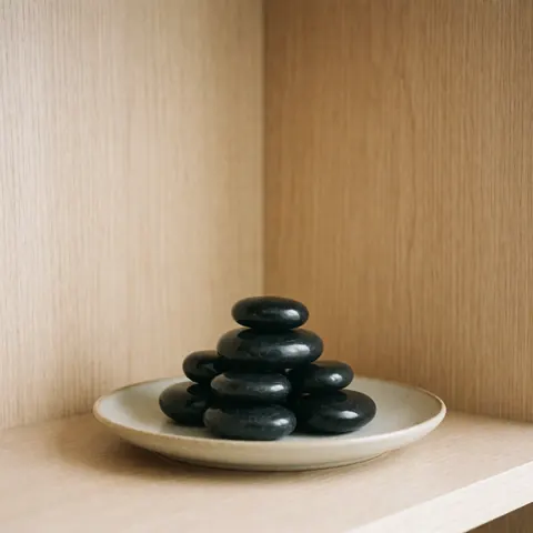 Des pierres volcaniques noires lisses disposées sur une surface en bois clair, créant une ambiance zen et relaxante pour un spa.