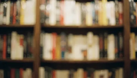 Fond d'étagères de librairie avec livres flous, couleurs chaudes, idéal pour textes ou titres.