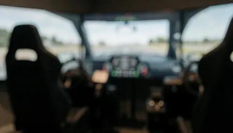 Vue intérieure d'un simulateur de conduite professionnel montrant un volant, un tableau de bord et des sièges sur un fond flou pour texte.