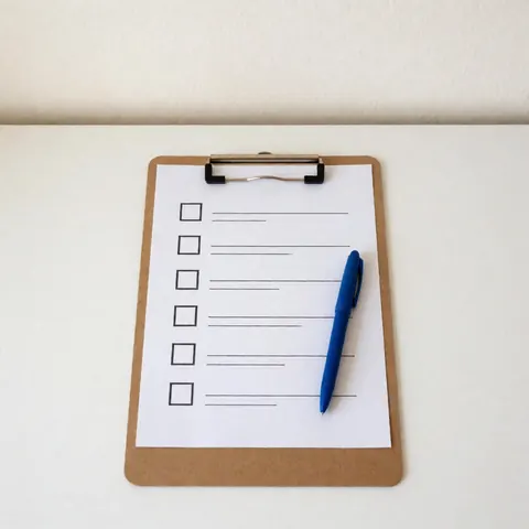 Vue de dessus d'un porte-documents en bois ouvert avec une liste de contrôle imprimée et un stylo posés à côté, évoquant l'organisation professionnelle.