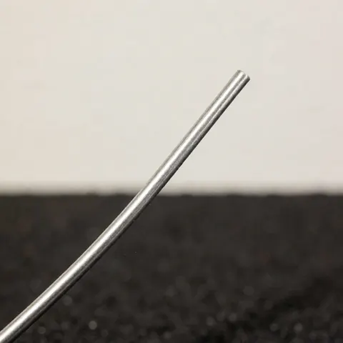 Gros plan sur une soudure métallique brillante avec du fil de soudage, montrant la texture et le fini sur un fond sombre.