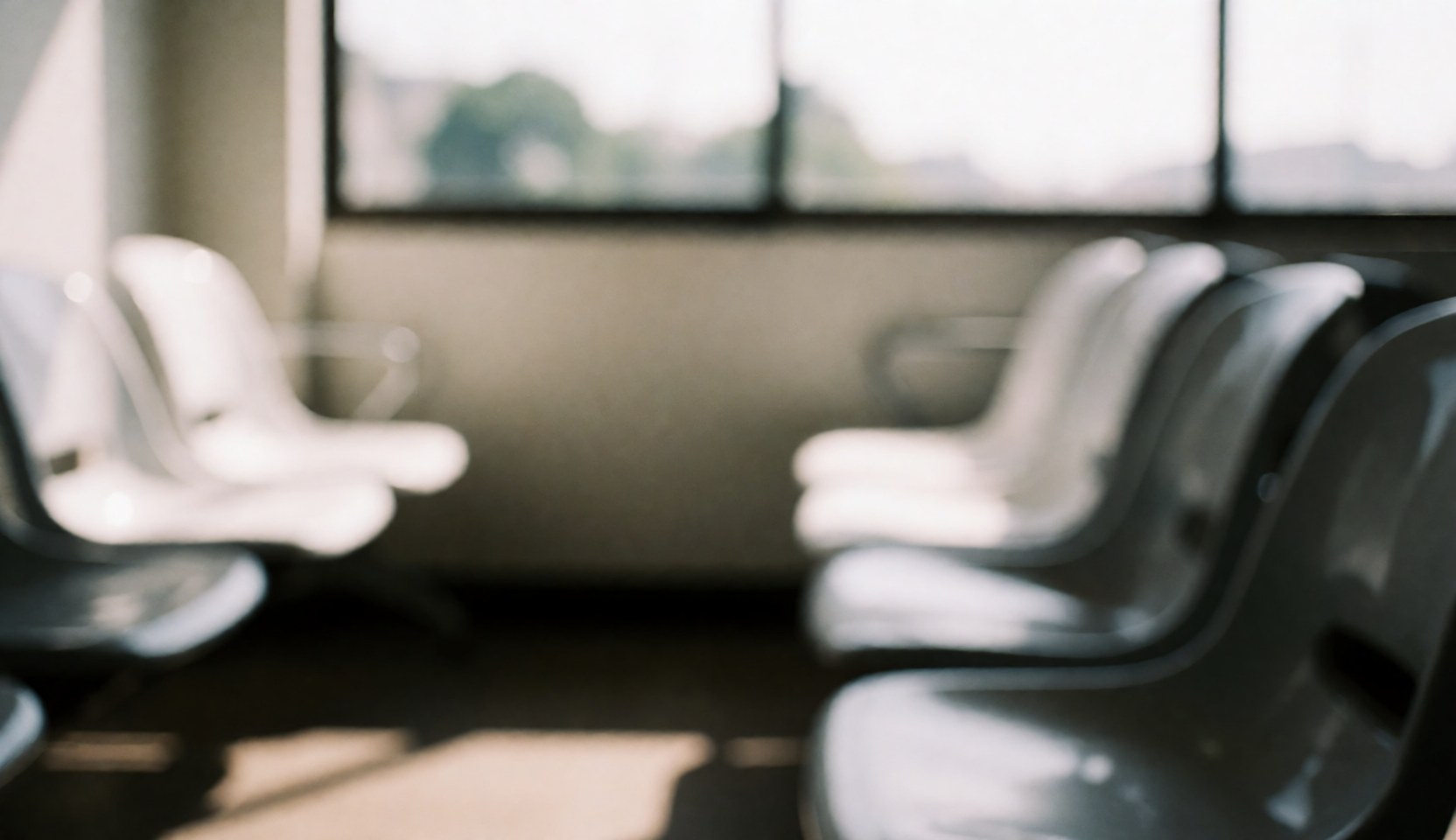 Fond neutre et calme d'une zone d'attente intérieure avec chaises en plastique, fenêtres et murs blancs et gris, idéal pour textes et présentations commerciales.