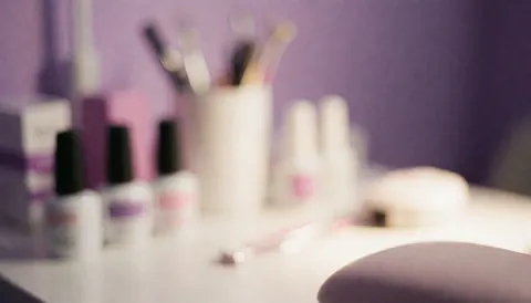 Arrière-plan flouté d'un salon de beauté violet et blanc présentant des outils et des produits de manucure, idéal pour supports promotionnels.