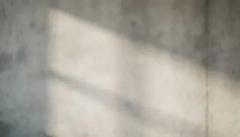 Fond de béton gris avec texture douce et ombres diffuses, idéal pour placer du texte commercial. Couleur neutre et propre, sans détails ni personnes.