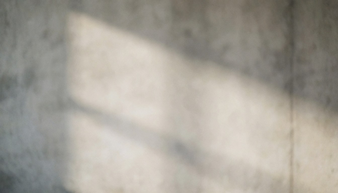 Fond de béton gris avec texture douce et ombres diffuses, idéal pour placer du texte commercial. Couleur neutre et propre, sans détails ni personnes.